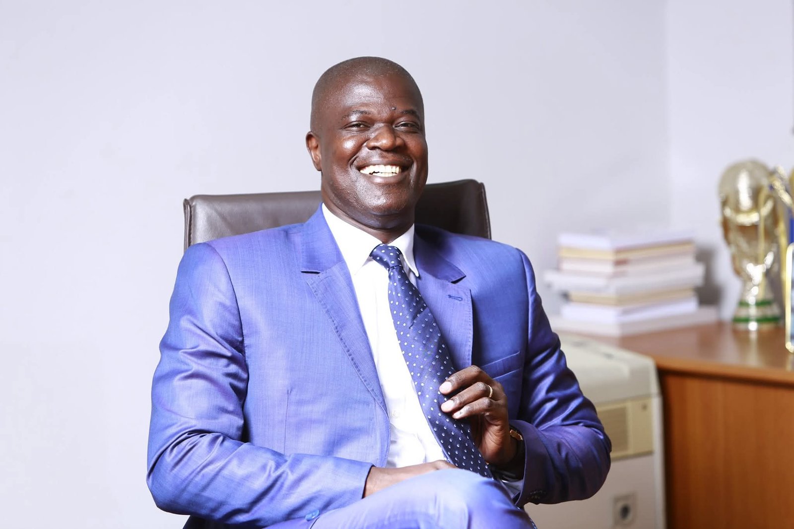 Eloge Beonao seated in a blue suit, smiling in an executive office